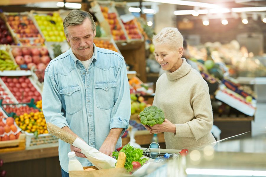 Älteres, fröhliches Päärchen kauft Lebensmittel in einem Supermarkt